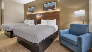 A hotel room with two beds, a desk, a chair, and a nightstand.