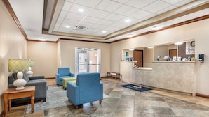 A hotel lobby with a reception desk, seating area, and a large window.
