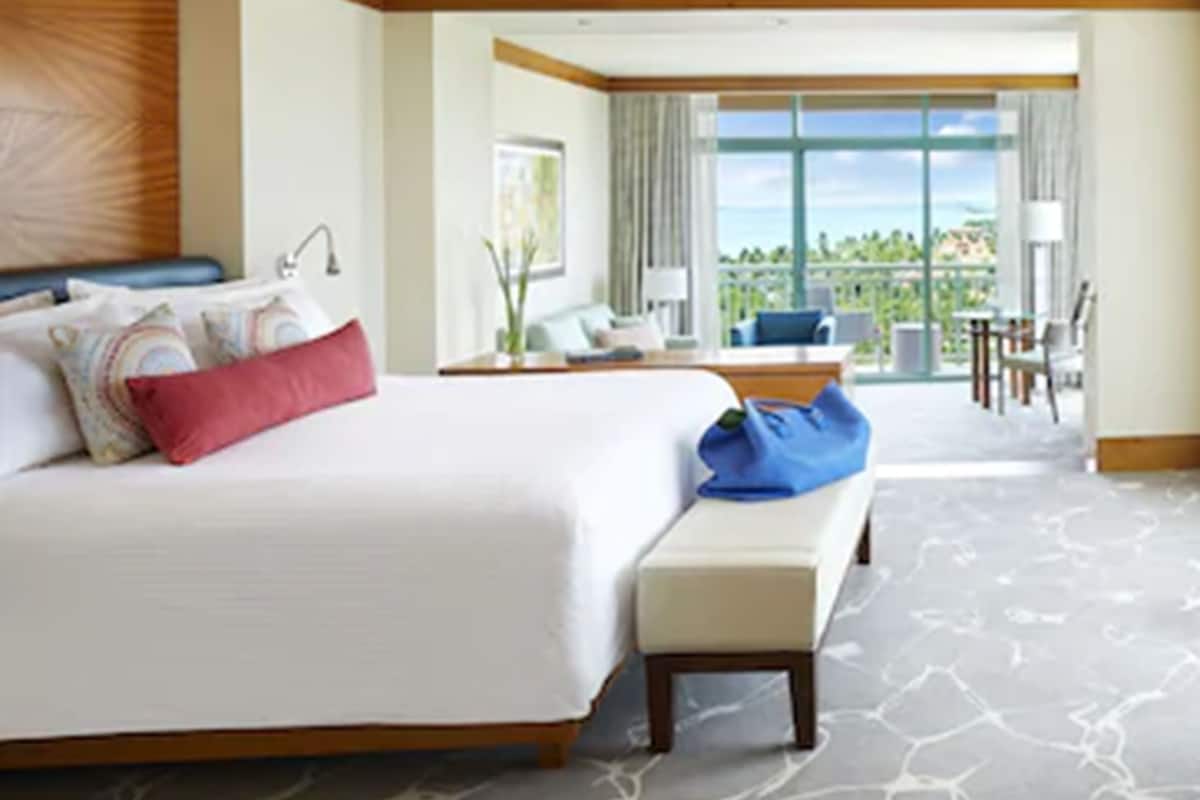 A hotel room with a large bed, a desk, and a balcony with a view.