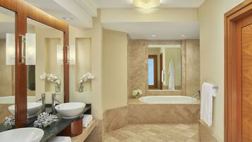 A modern bathroom with two sinks, a bathtub, and a large mirror.