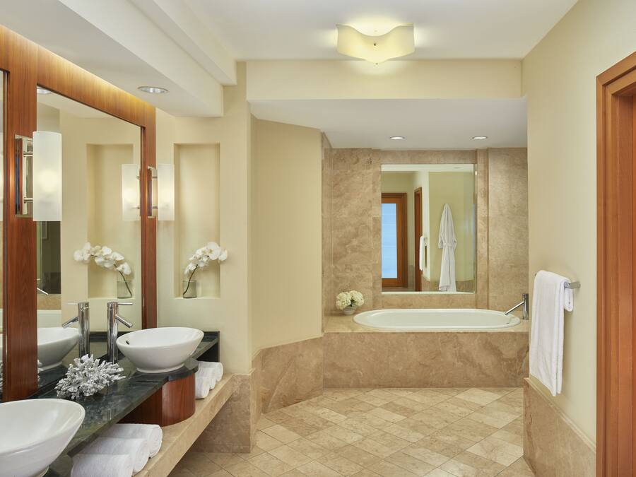 A modern bathroom with two sinks, a bathtub, and a large mirror.