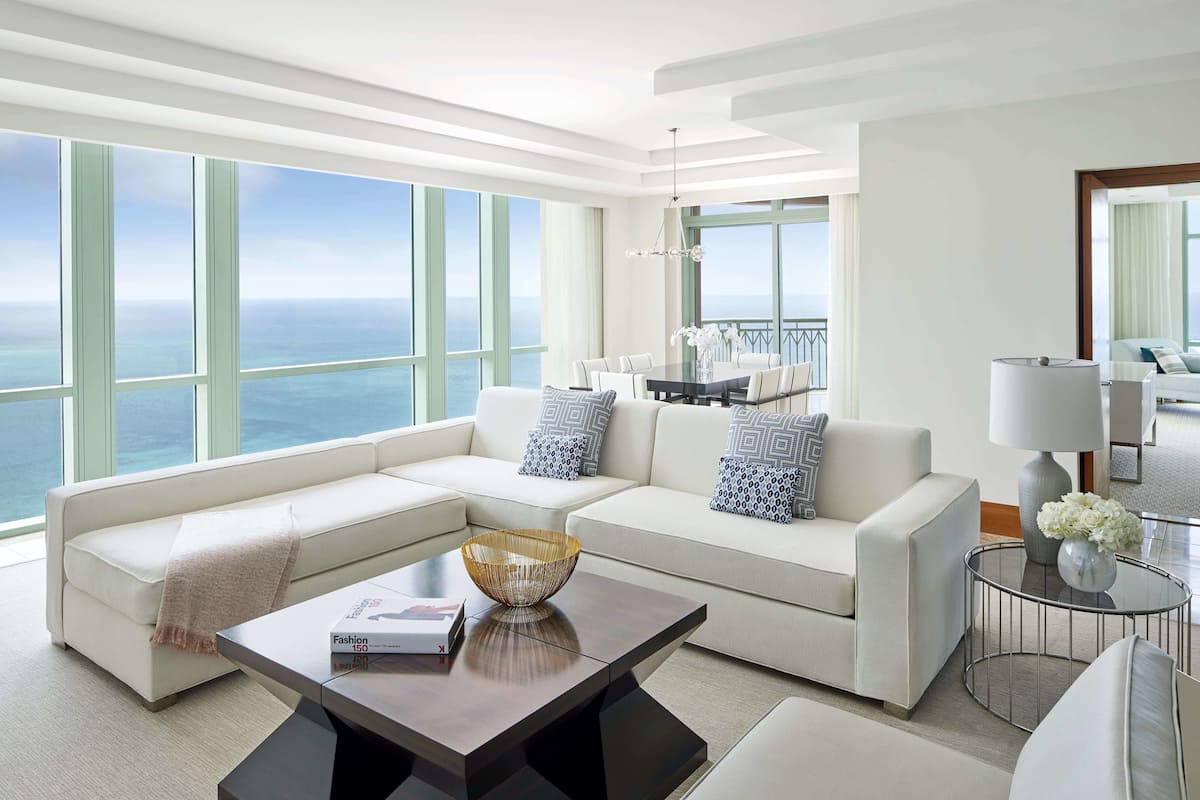 A modern living room with a large sectional sofa, a coffee table, and a view of the ocean.