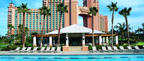 A hotel with a swimming pool, palm trees, and a large building with multiple towers.