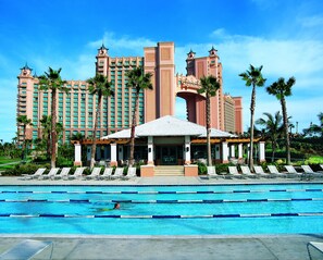 A hotel with a swimming pool, palm trees, and a large building with multiple towers.