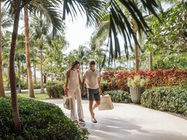 Una pareja caminando por un sendero rodeado de abundante vegetación y palmeras.