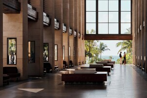 A spacious lobby with high ceilings, large windows, and a view of the ocean.