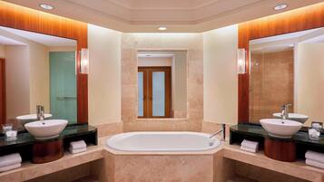 Un baño moderno con dos lavamanos, una bañera grande y un espejo sobre la bañera.