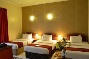 Habitación de hotel con dos camas, un escritorio y una mesita de noche.