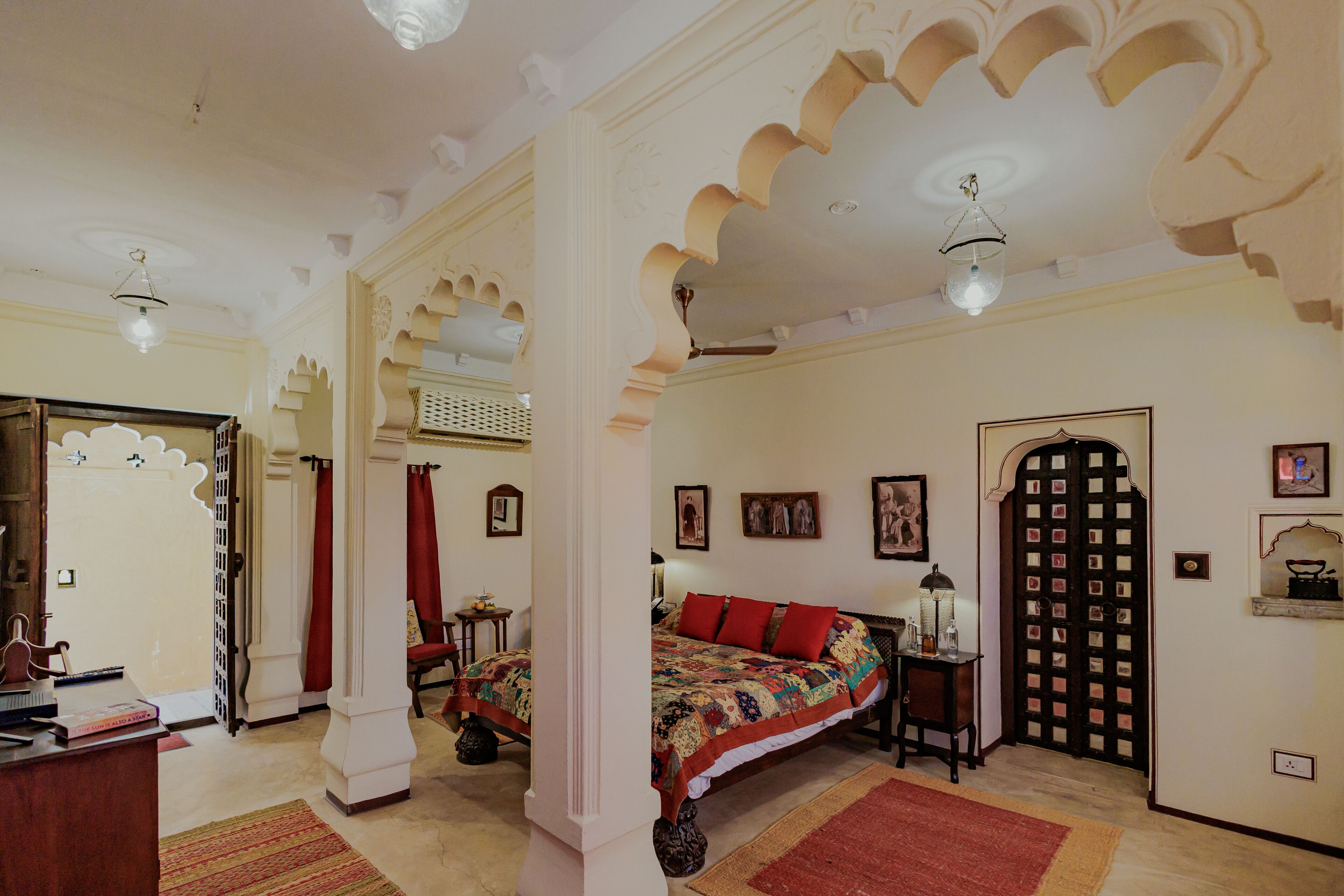 A traditional room with a bed, a desk, and a door with intricate designs.