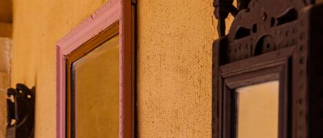 Two wall-mounted mirrors with ornate frames against a textured wall.