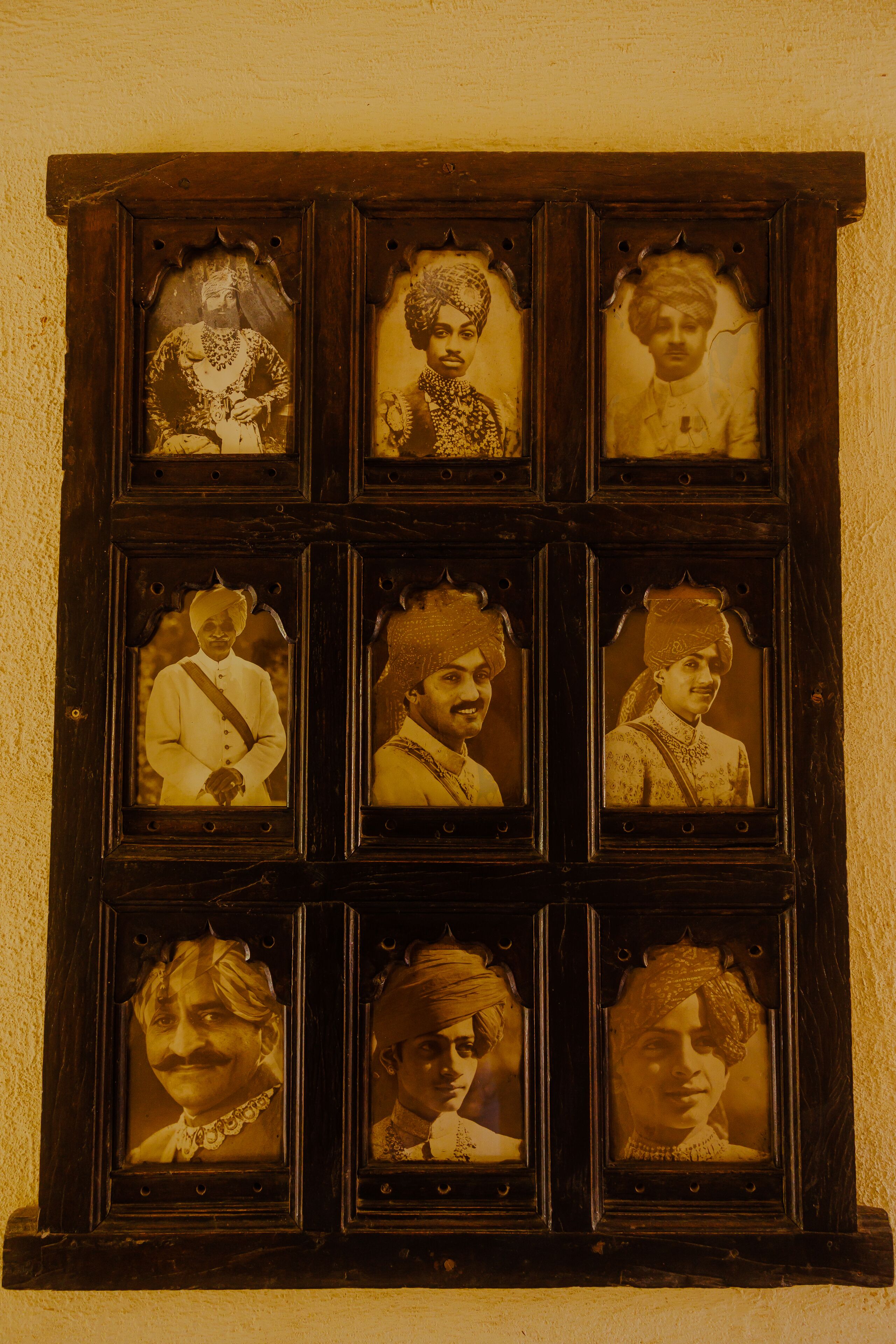 Uma vitrine de madeira com seis fotografias emolduradas de pessoas vestindo trajes típicos.