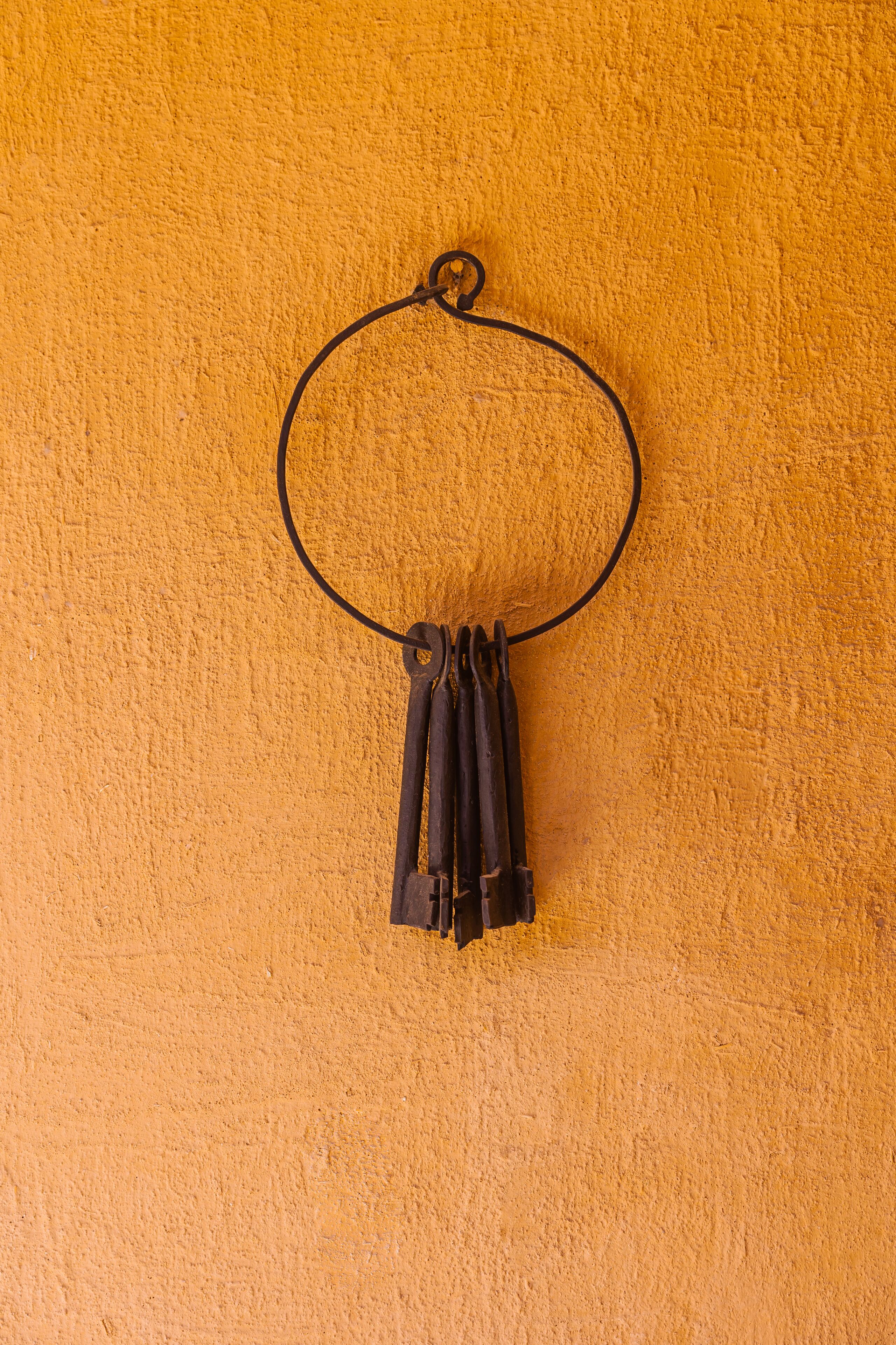 A black circular object hanging on a textured orange wall.
