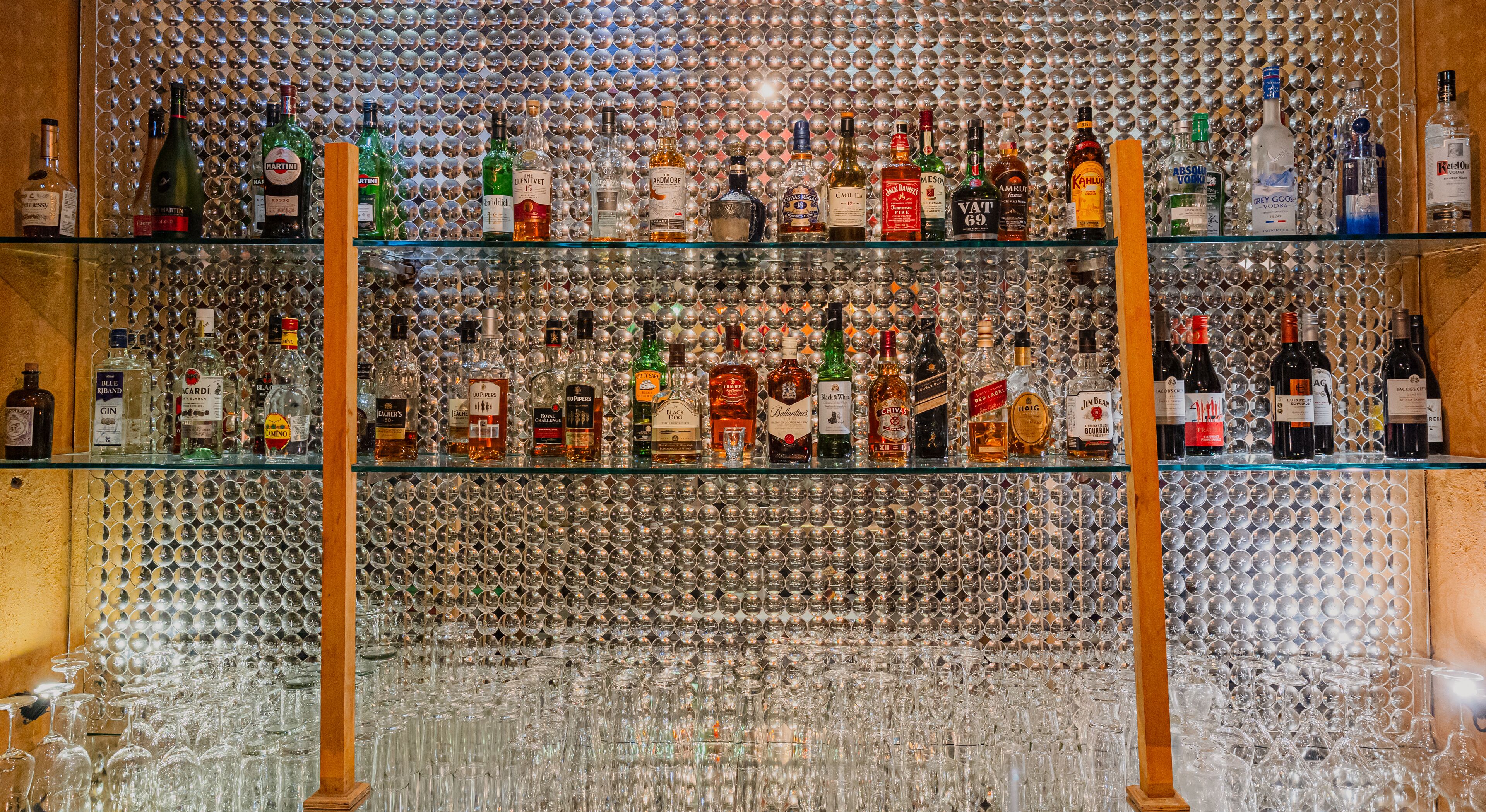 Un bar con numerosas estanterías repletas de botellas de licores.