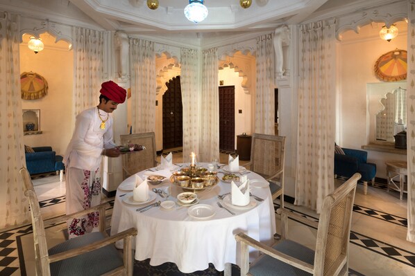 A dining area with a round table set for a meal, surrounded by ornate chairs. - Rawla Narlai (Desuri)