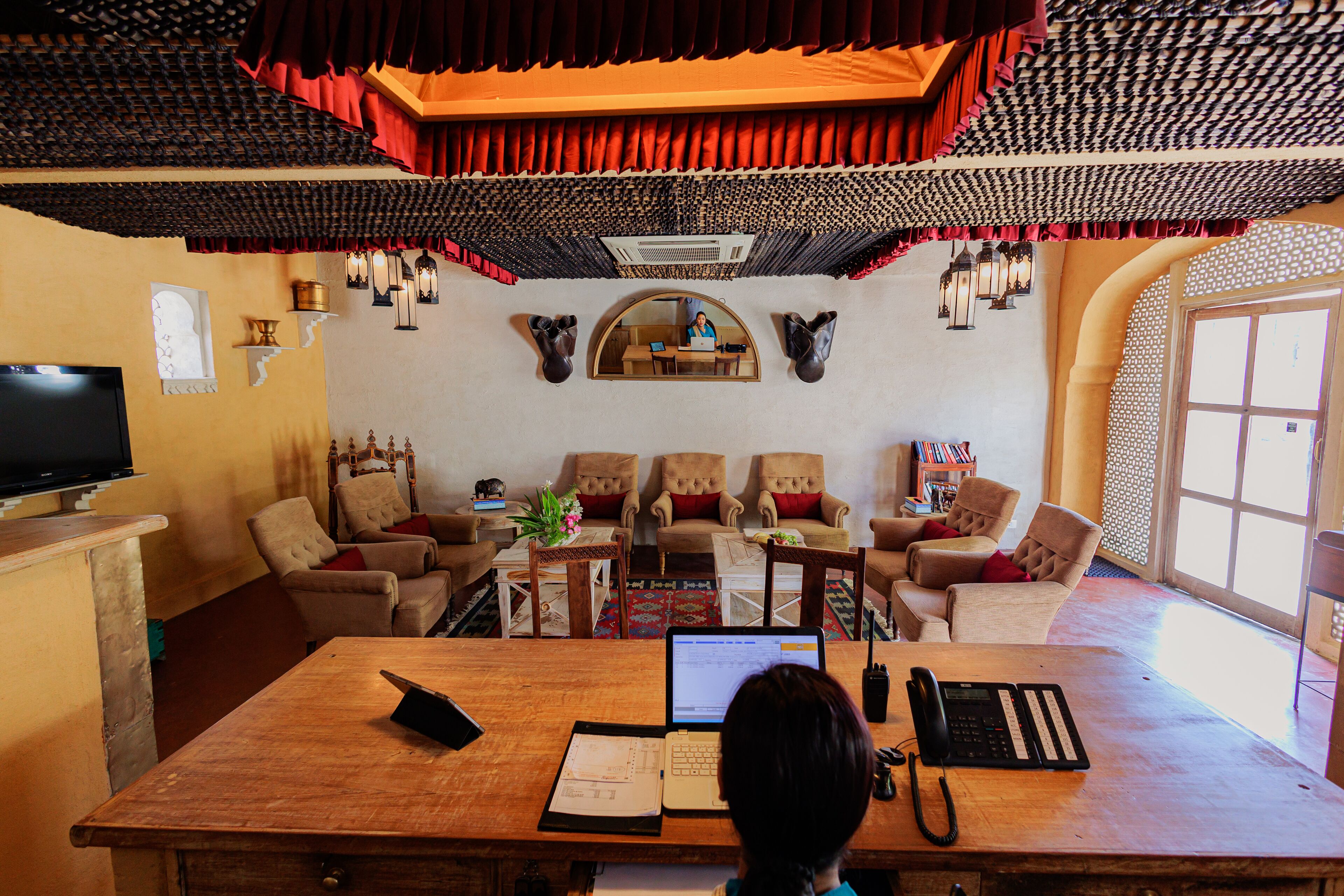 Un intérieur traditionnel avec un bureau en bois, des chaises, un téléviseur et une grande fenêtre.