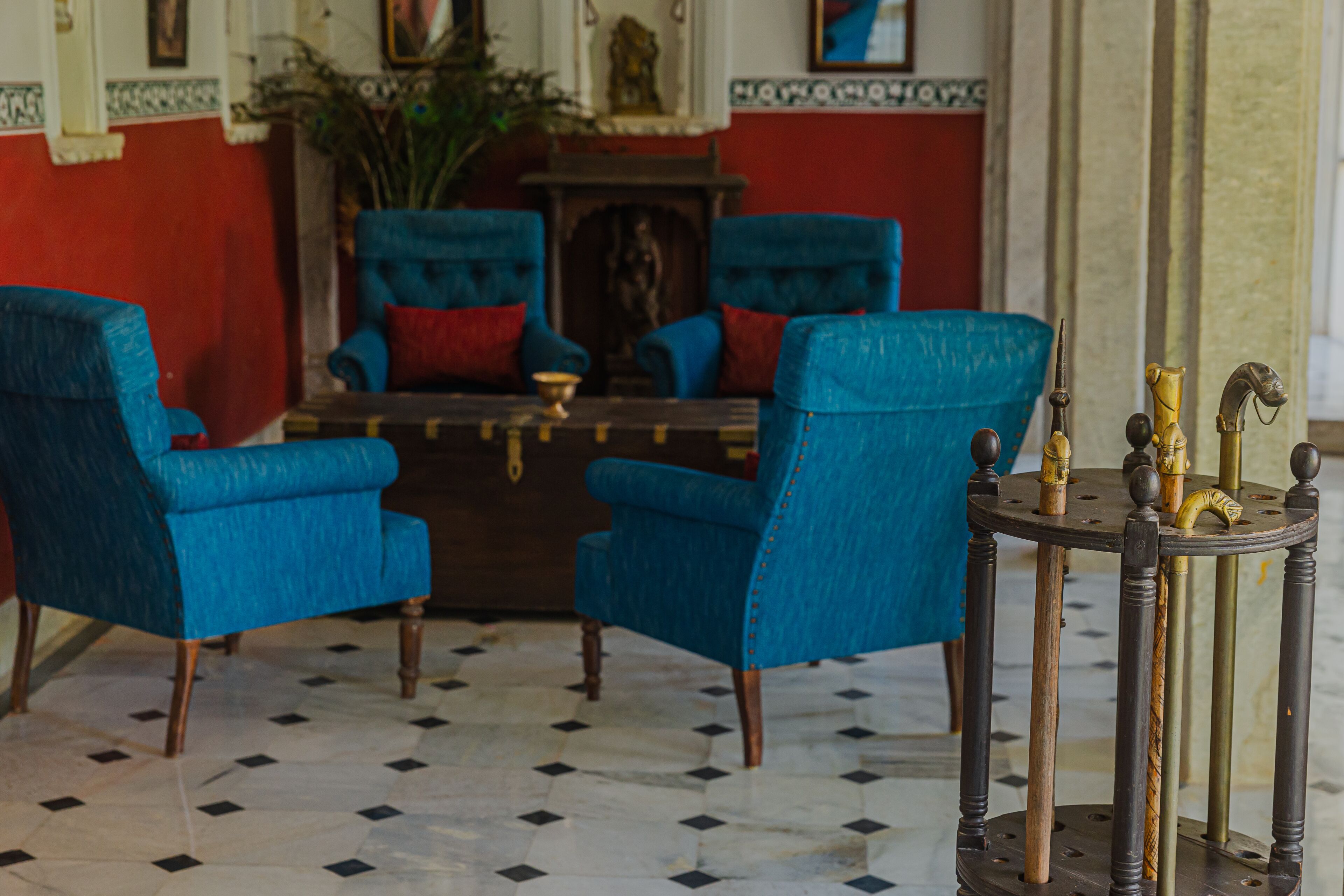 A room with blue armchairs, a small round table with decorative items, and a tiled floor.