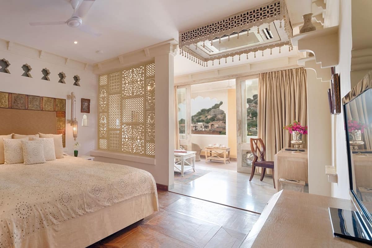 A bedroom with a large bed, a nightstand, a decorative headboard, and a view of the outside.