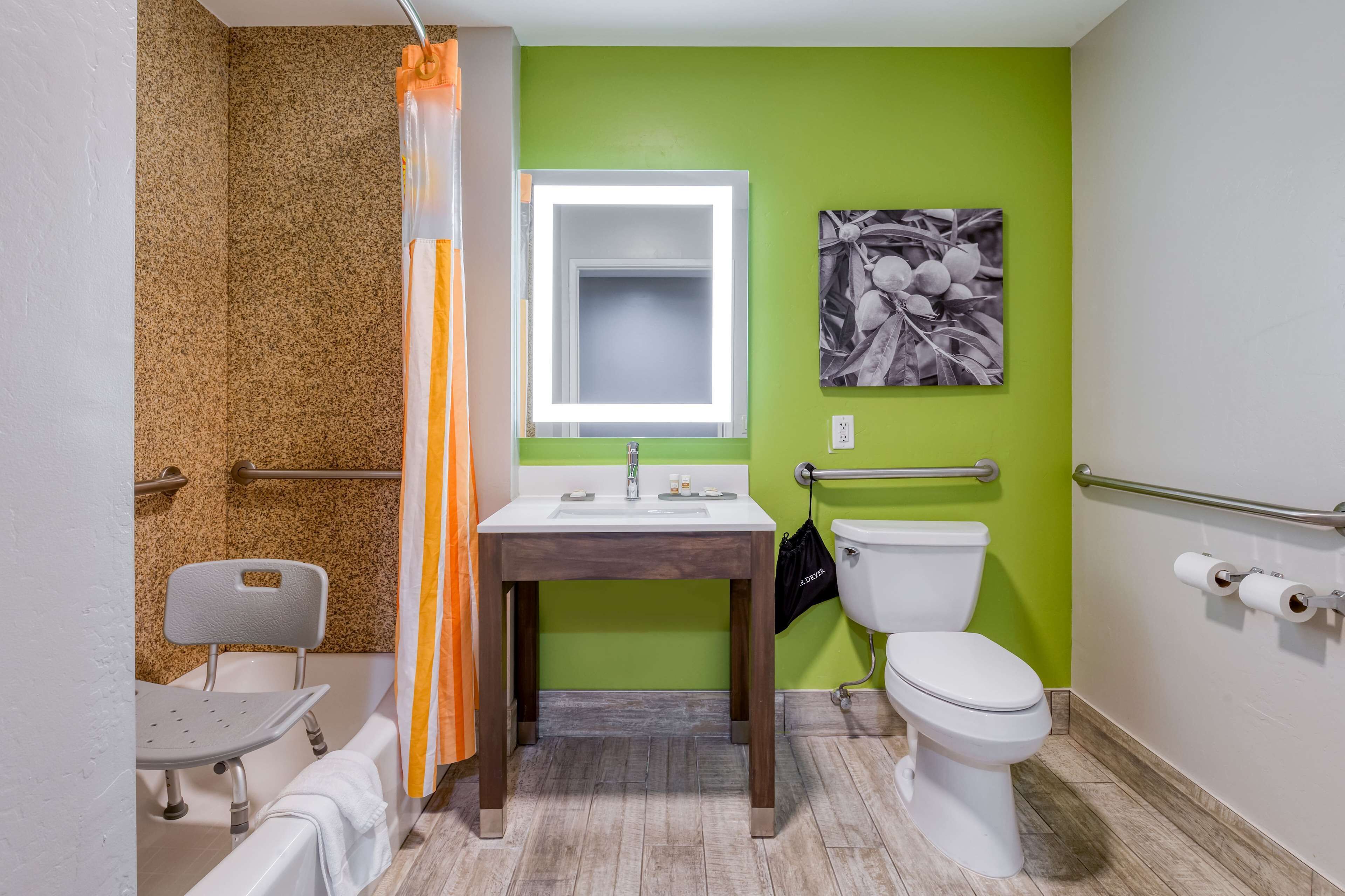 Ein Badezimmer mit grüner Wand, Waschbecken in Weiß, Toilette und Dusche.