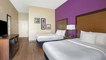 A hotel room with two beds, a TV, a desk, and a bathroom.
