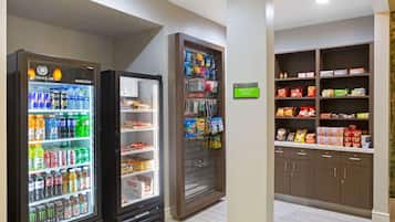 Une petite cuisine équipée d’un réfrigérateur pour les boissons, d’un distributeur automatique de collations et d’un garde-manger rempli de produits alimentaires.