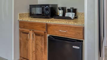 Una cocina con microondas, cafetera y tazas de café sobre la encimera.