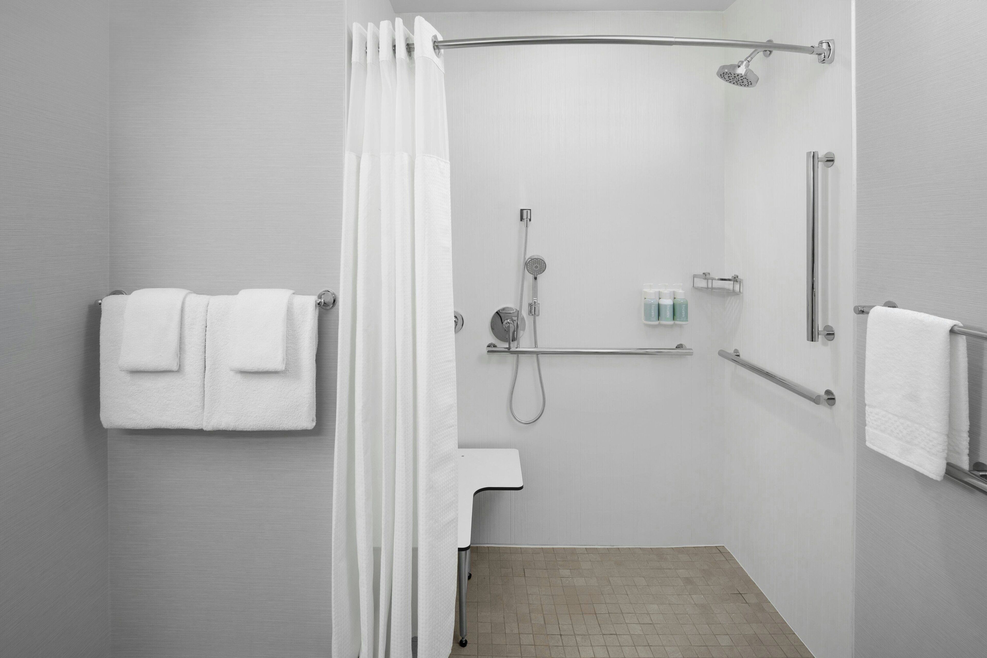 Un baño moderno con ducha, barras de apoyo y un perchero para toallas.
