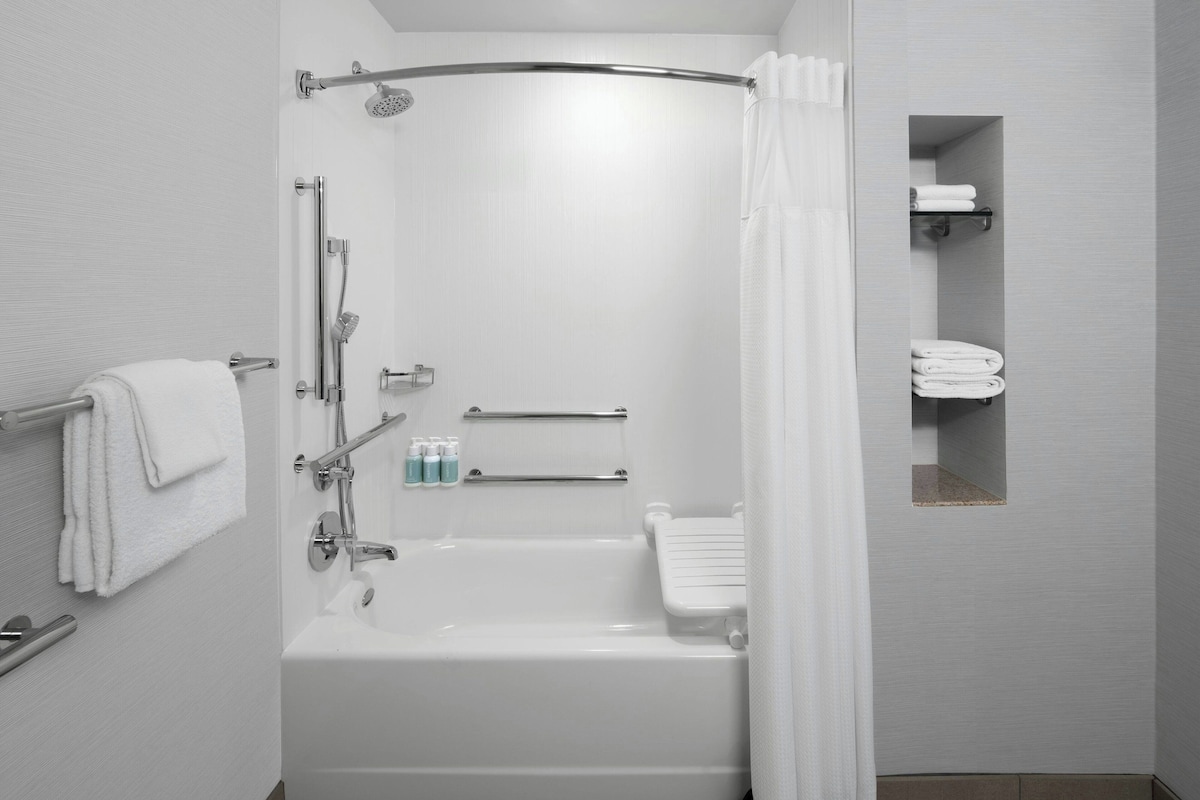Een moderne badkamer met een bad, douche en toilet.