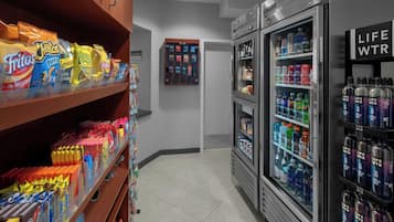 A snack aisle with chips and candy, a vending machine, and refrigerated drinks.
