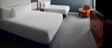 Ein Hotelzimmer mit zwei Betten, einem Schreibtisch, einem Stuhl, einem Fernseher und einer Lampe.