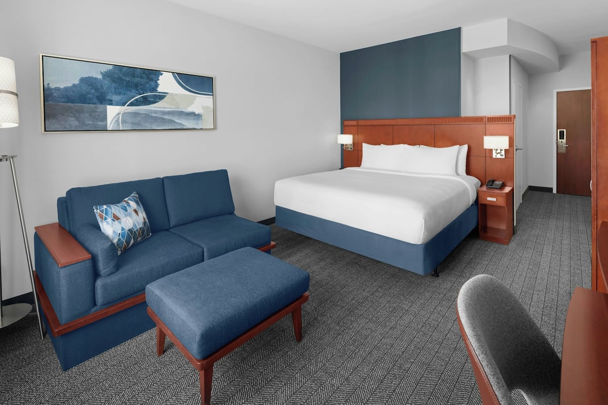 Een hotelkamer met een groot bed, een bank, een bureau en een stoel.