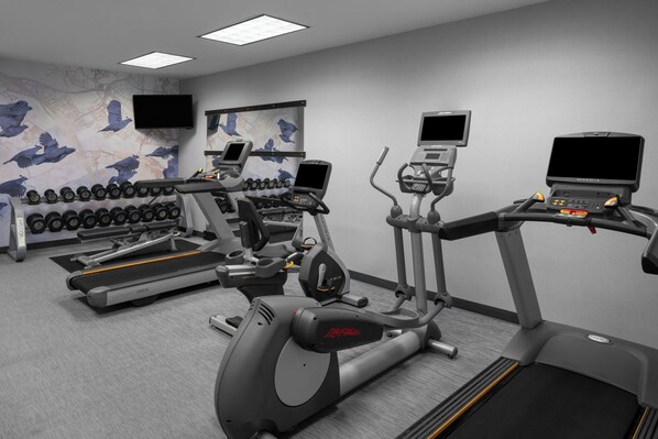 Un gimnasio con cintas de correr, elípticas y mancuernas.