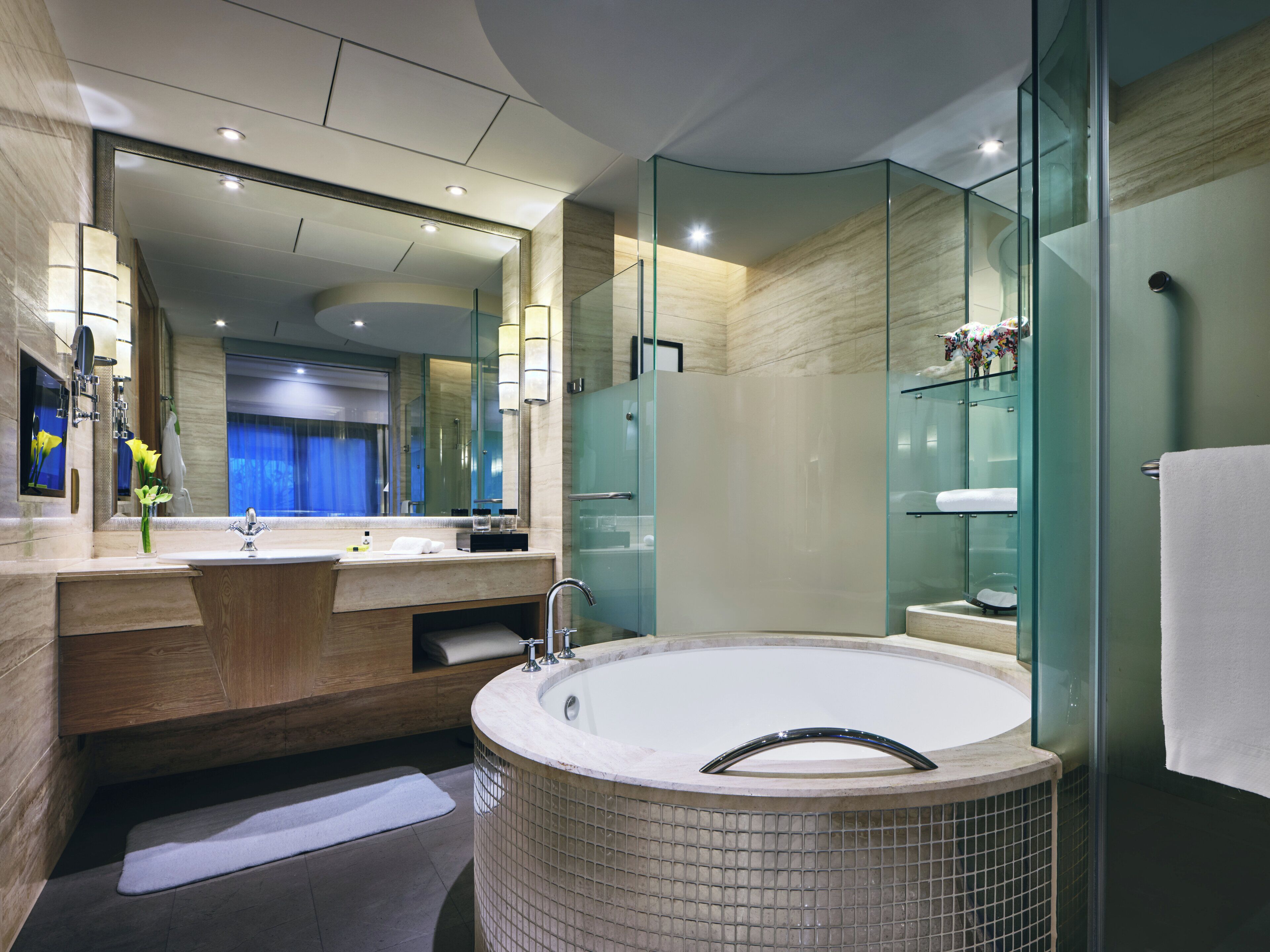 Een moderne badkamer met een groot bad, een douche met glazen wand en een wastafel met spiegel.