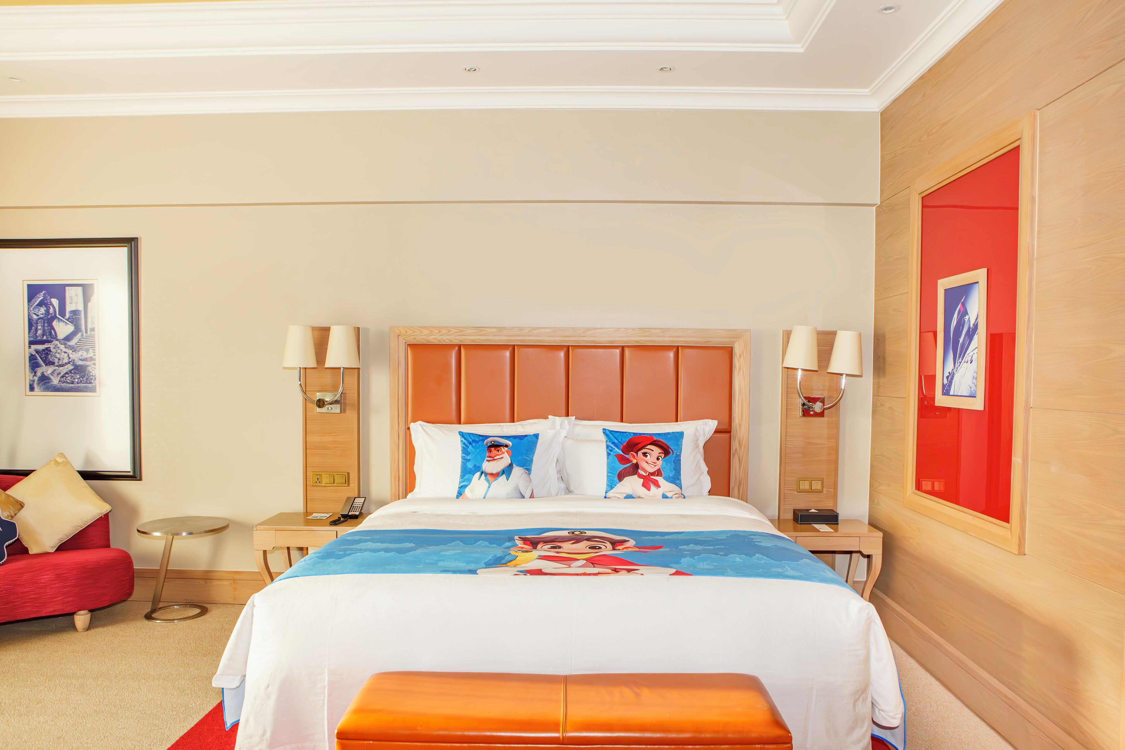 Ein Hotelzimmer mit einem großen Bett, einem roten Sofa, einem kleinen runden Tisch und zwei Nachttischlampen.