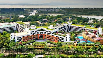 A hotel with multiple buildings, a swimming pool, and a large body of water in the background.