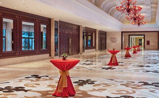A spacious hallway with traditional wooden doors and a red carpeted floor.