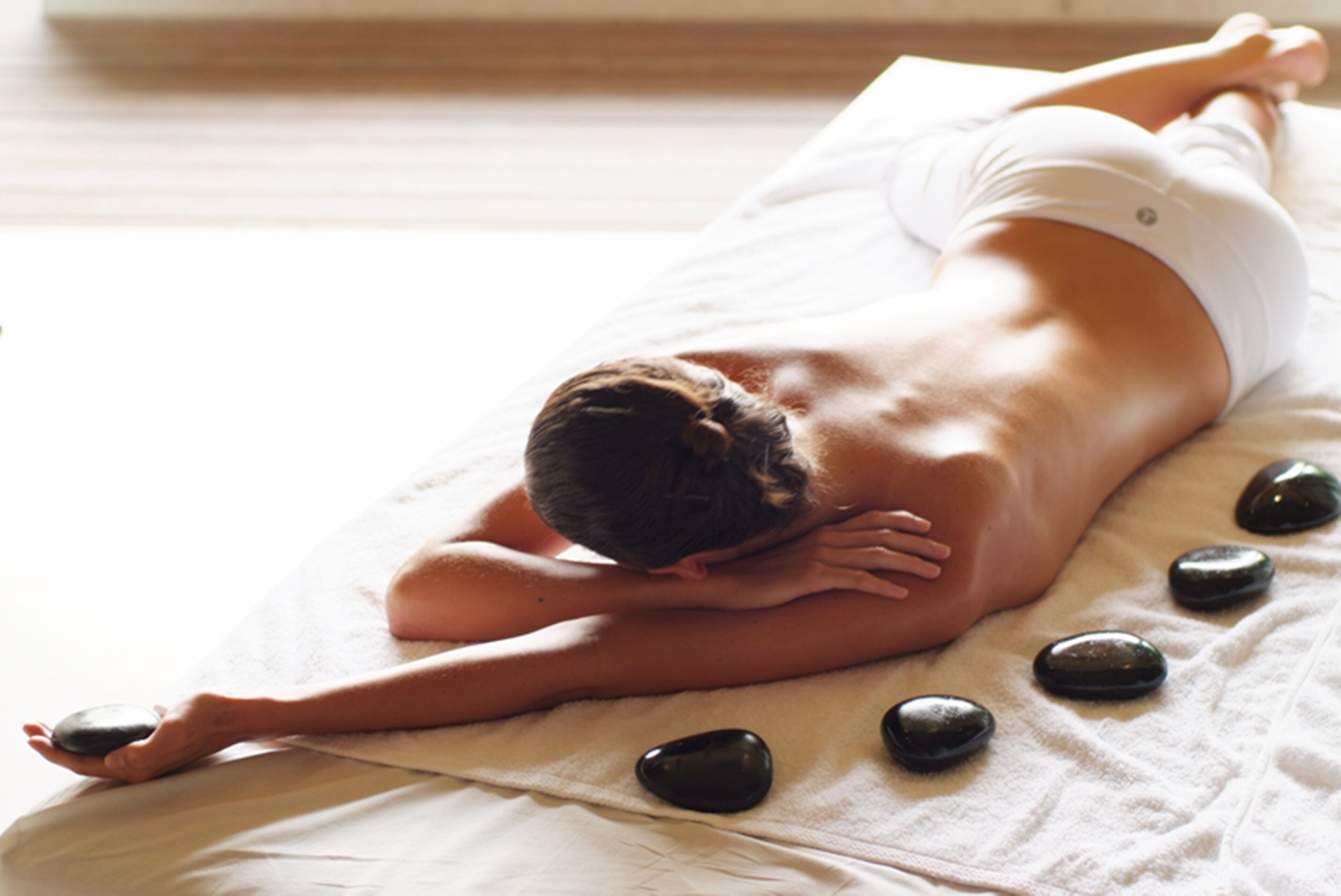 A person receiving a back massage on a bed with stones.