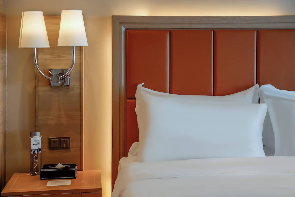 A hotel room with a bed, a nightstand, a lamp, and a tissue box.