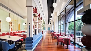 A modern restaurant with a long counter, red and blue seating, and large windows offering a view of the outdoors. - InterContinental Shenzhen by IHG (Shenzhen)