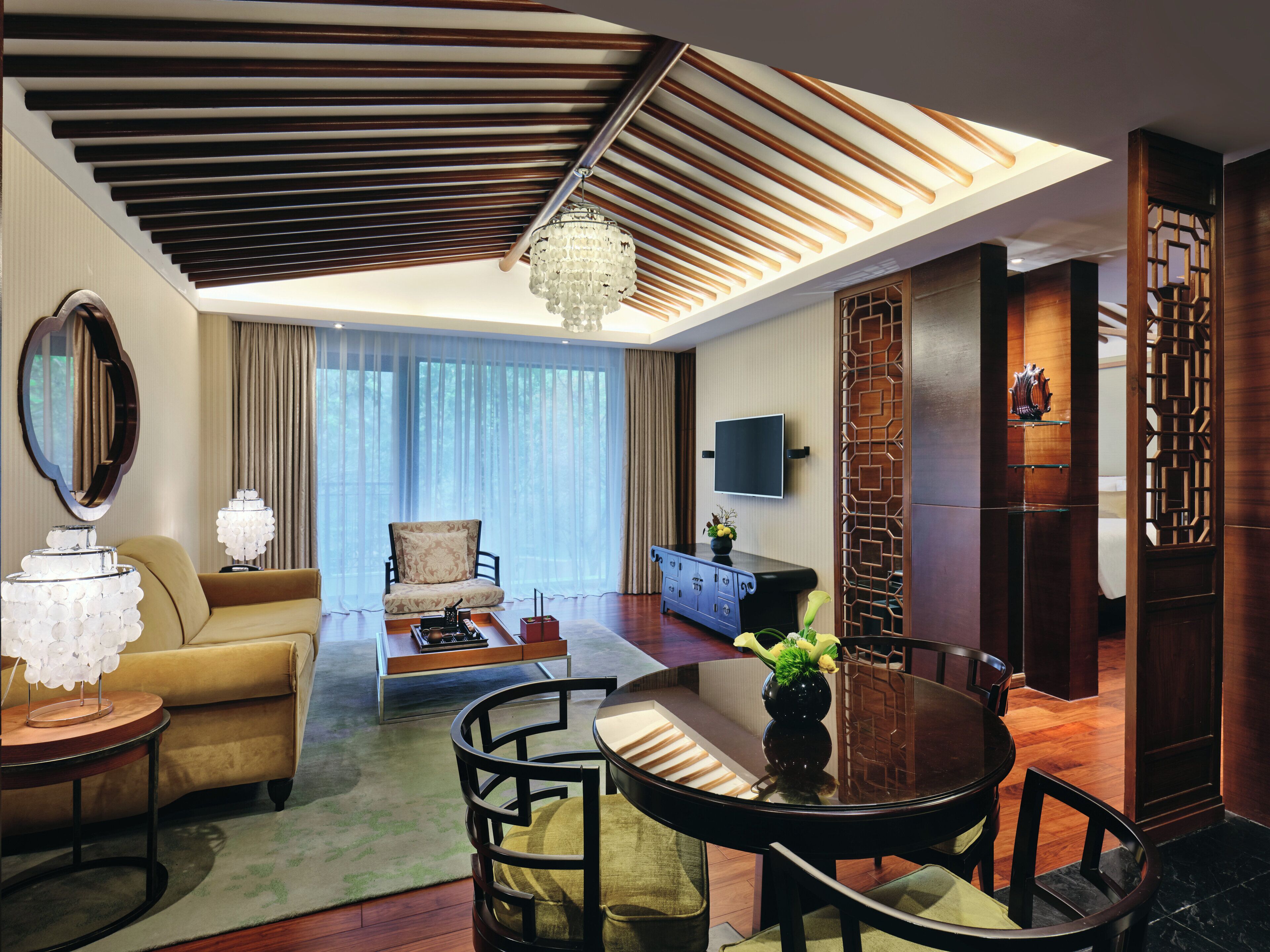 A modern living room with a sofa, a round dining table, and a chandelier.