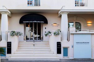 The entrance of the Terrazzamarconi Hotel & Spa with a grand archway, steps leading up to the entrance, and a sign above the door.
