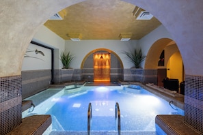 A spa pool with a tiled interior, a central water feature, and a seating area with a view of the pool.