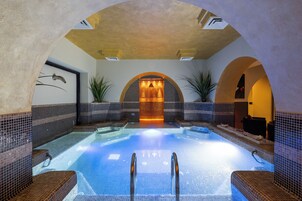 Un jacuzzi con interior de azulejos, un elemento central de agua y una zona de estar con vistas a la piscina.