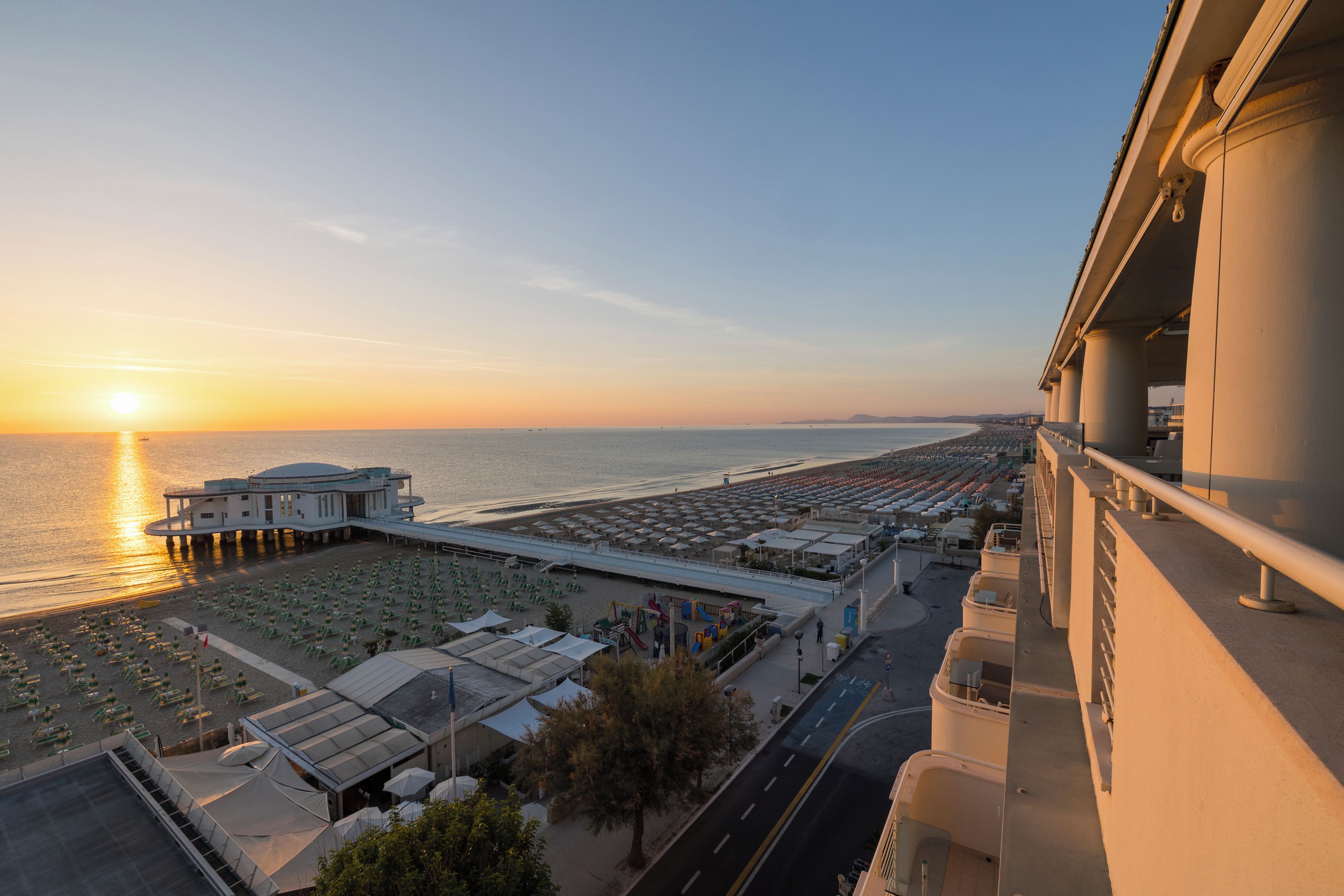 Un hotel frente al mar con vista a la playa, un muelle y una zona de estacionamiento.