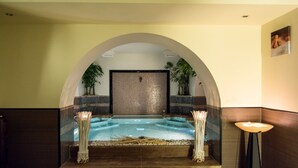 Un espacio de spa con hidromasaje, asientos y plantas.