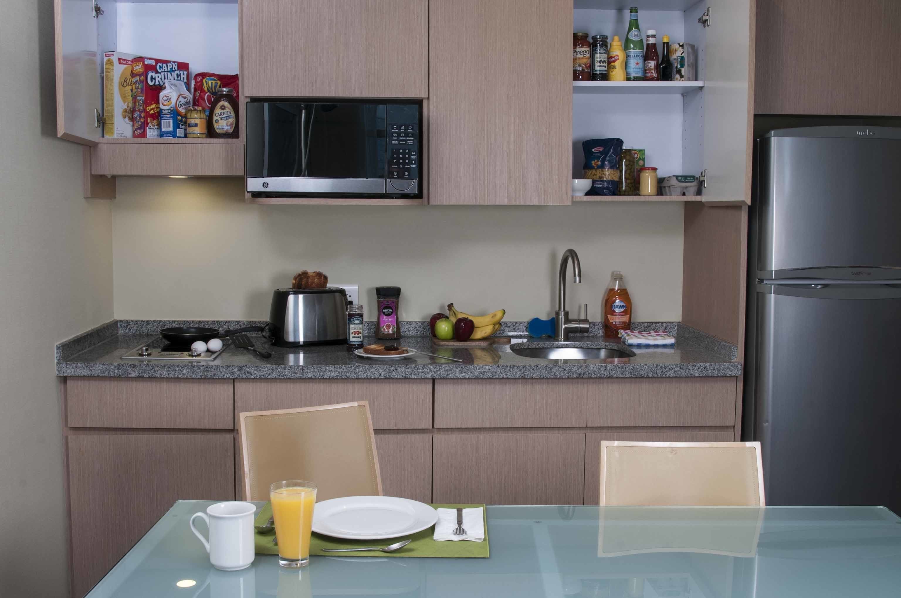 Cocina compacta con microondas, tostadora, lavamanos y refrigerador.