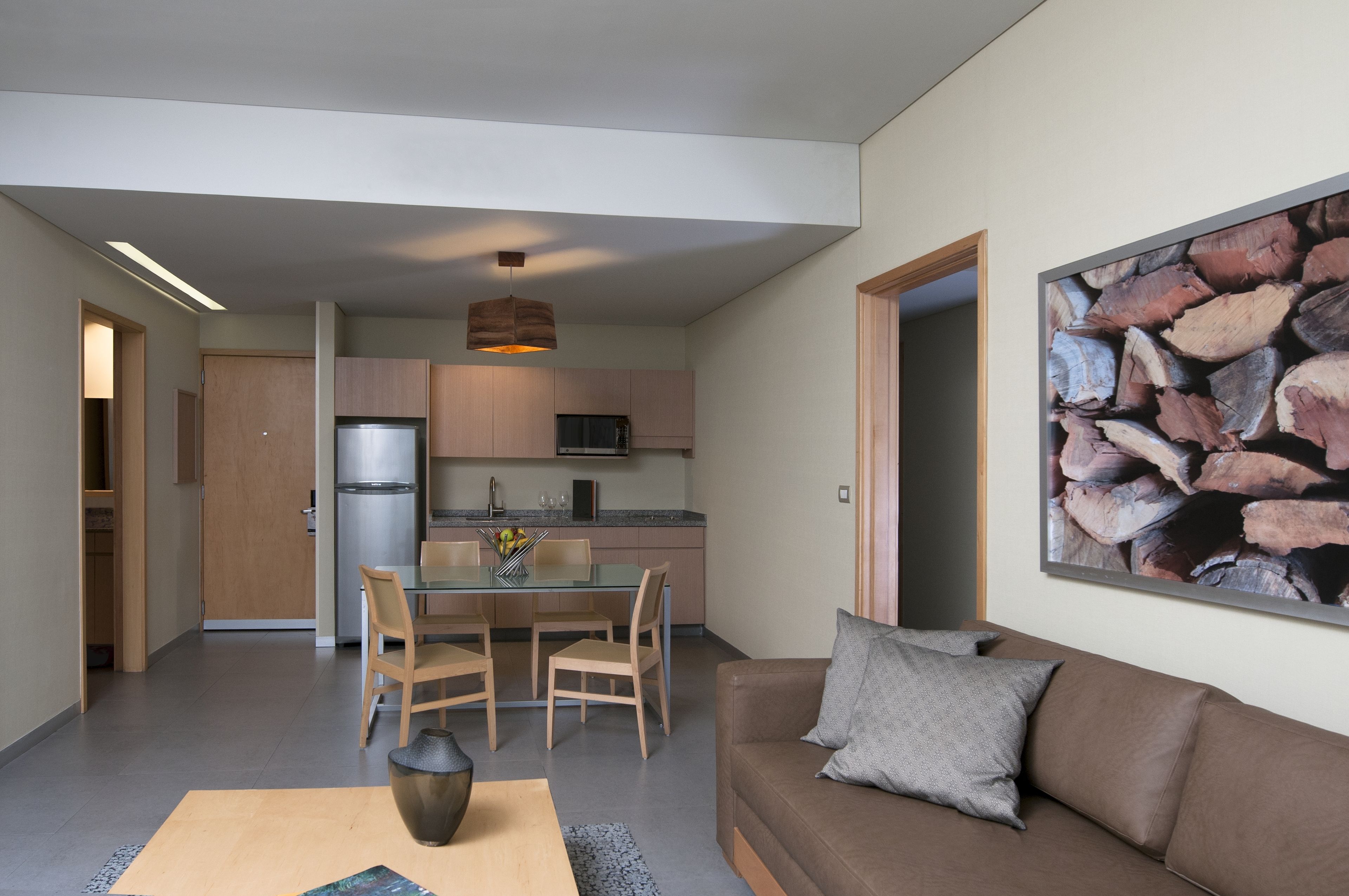 Een moderne keuken met houten kastjes, een roestvrijstalen koelkast en een eethoek met een glazen tafel en stoelen.