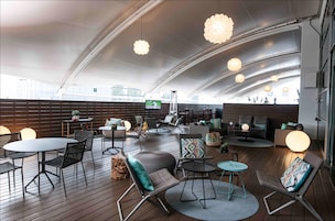 A spacious indoor area with wooden flooring, multiple seating arrangements including tables and chairs, and hanging spherical light fixtures.