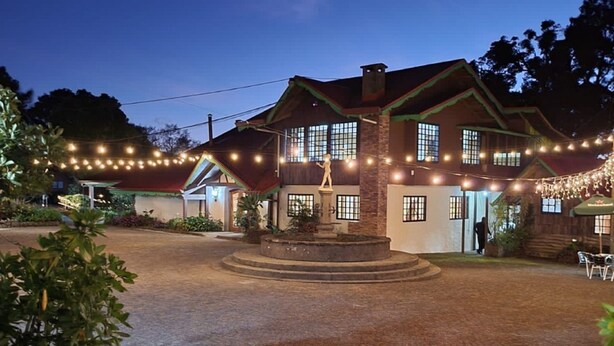 A two-story building with a brick facade, a central entrance with steps, and string lights. - Hotel El Tirol (Ángeles)