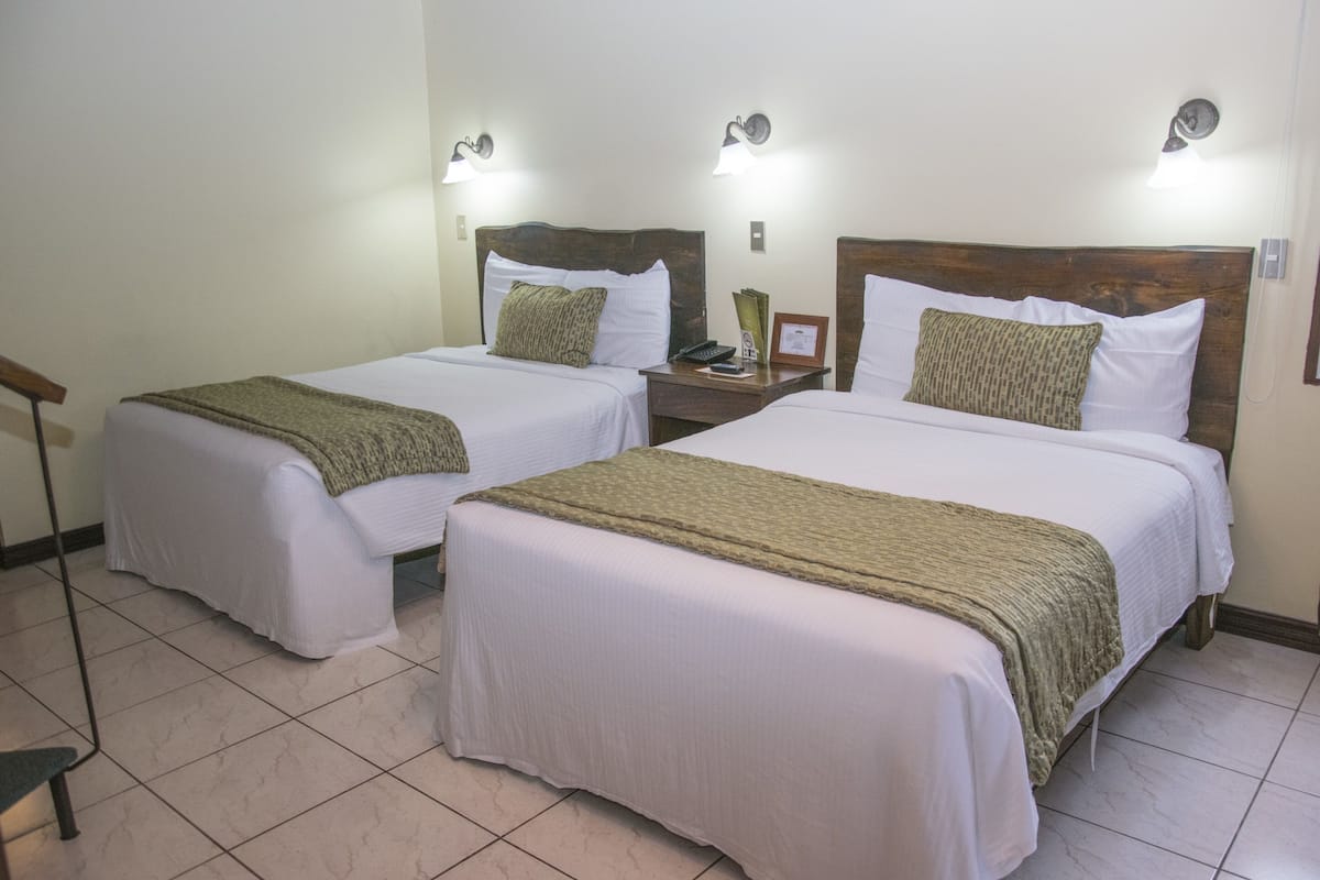 Two single beds with wooden headboards, white linens, and green throw blankets.