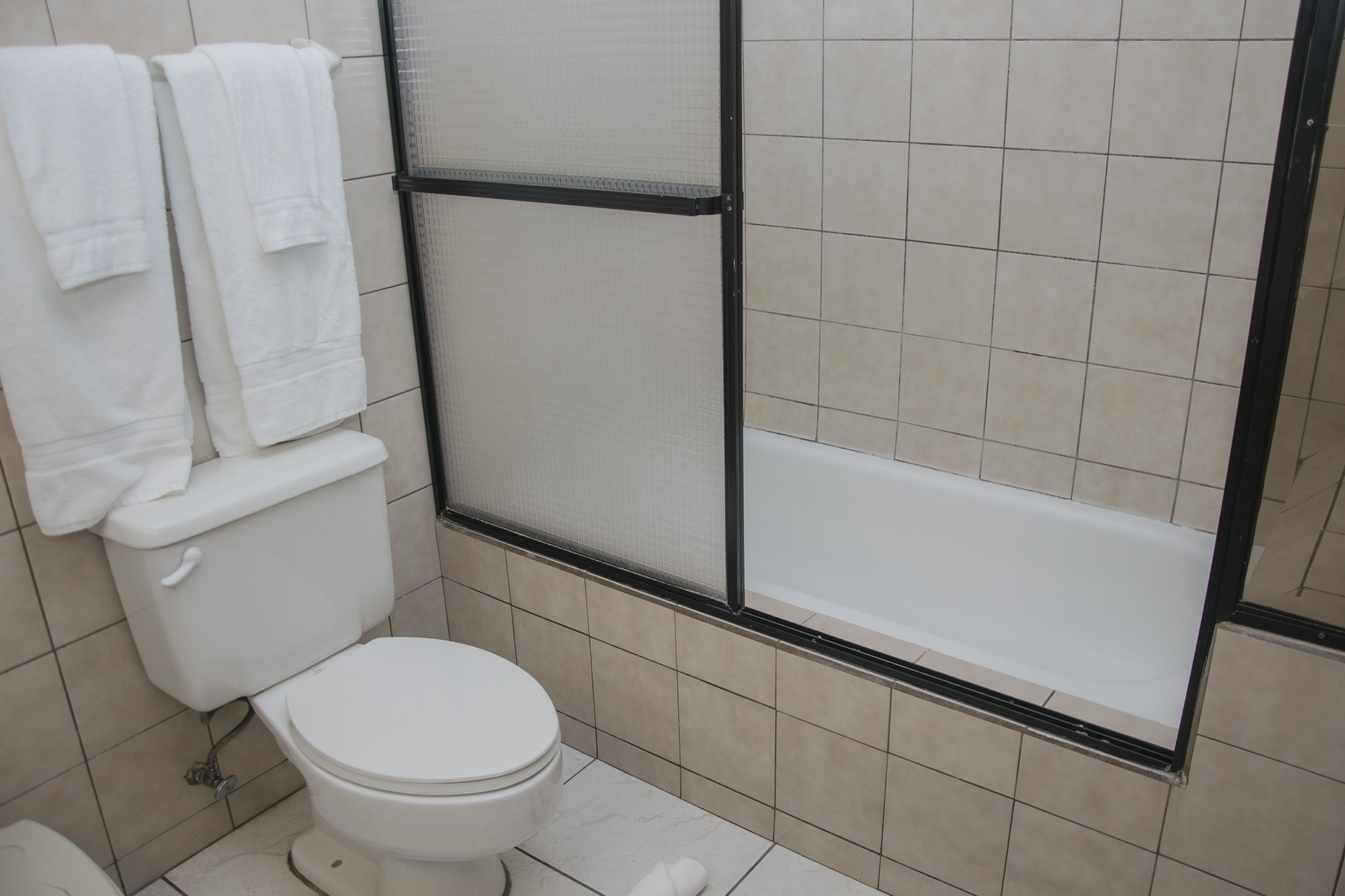 Un baño con inodoro, bañera y dos toallas colgadas en la pared.